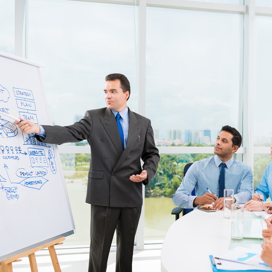 Hands-on training and support session with a trainer explaining concepts on a whiteboard to professionals